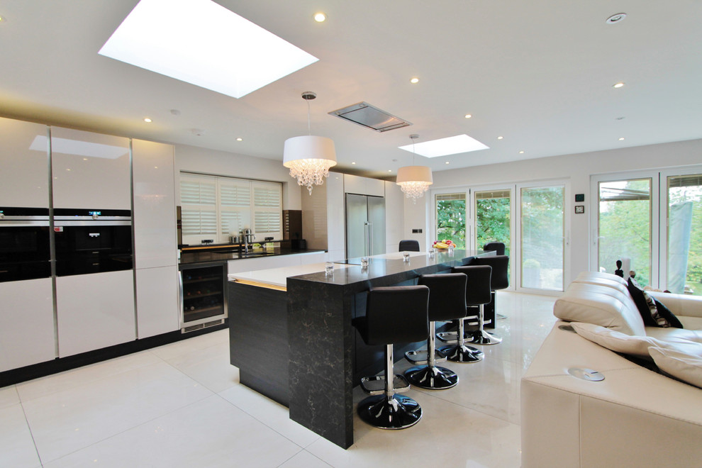 Photo of a large contemporary single-wall open plan kitchen in London with a submerged sink, flat-panel cabinets, white cabinets, quartz worktops, black appliances, porcelain flooring, an island, white floors and white worktops.