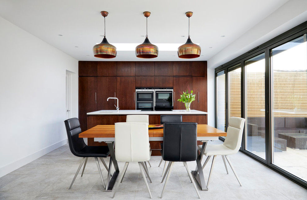 Идея дизайна: параллельная кухня-гостиная в современном стиле с плоскими фасадами, темными деревянными фасадами, черной техникой, островом и серым полом