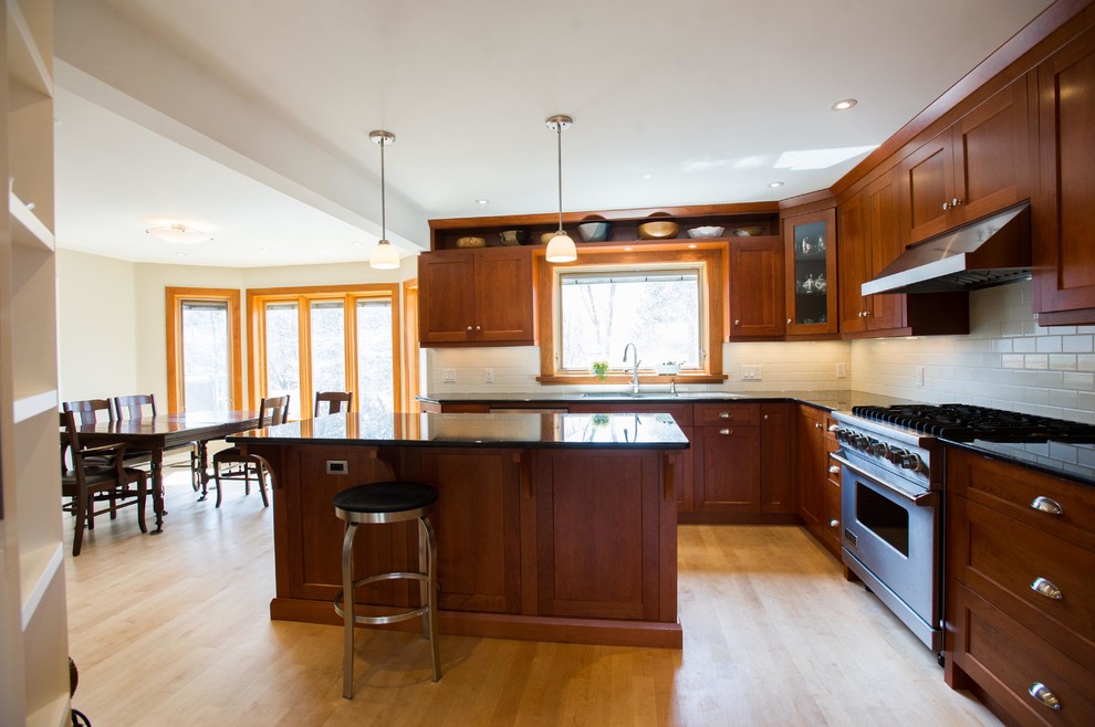 Example of a large classic l-shaped light wood floor eat-in kitchen design in Toronto with an undermount sink, shaker cabinets, medium tone wood cabinets, granite countertops, white backsplash, porcelain backsplash, stainless steel appliances and an island