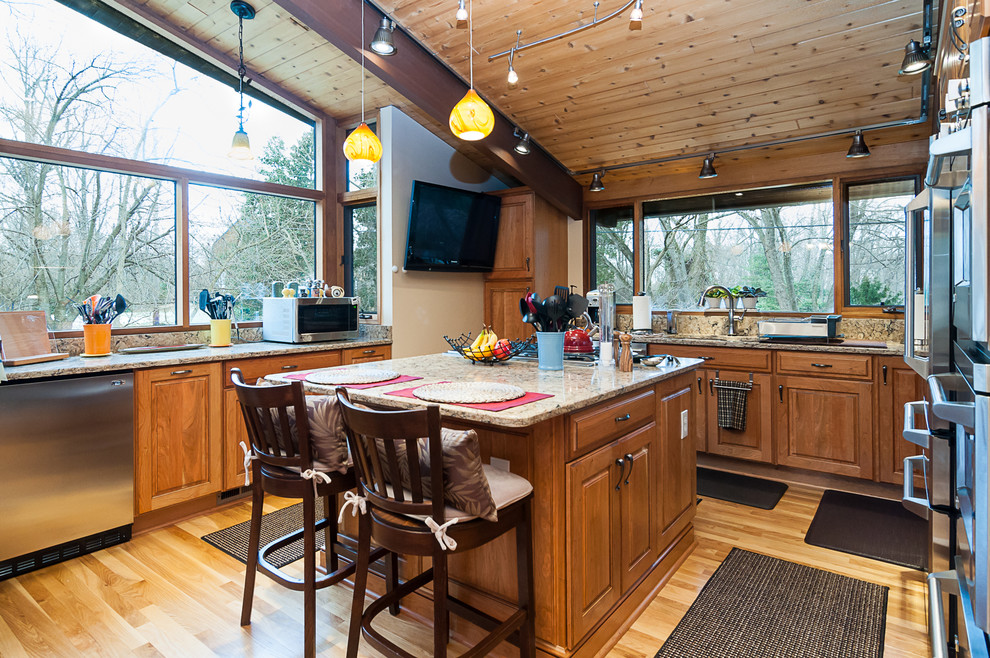 Bild på ett mellanstort amerikanskt kök, med en undermonterad diskho, luckor med upphöjd panel, skåp i ljust trä, bänkskiva i kvarts, rostfria vitvaror, ljust trägolv, en köksö och beiget golv