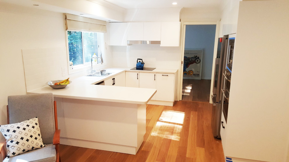 Immagine di una cucina minimal di medie dimensioni con ante lisce, ante bianche, paraspruzzi bianco, nessuna isola e top bianco