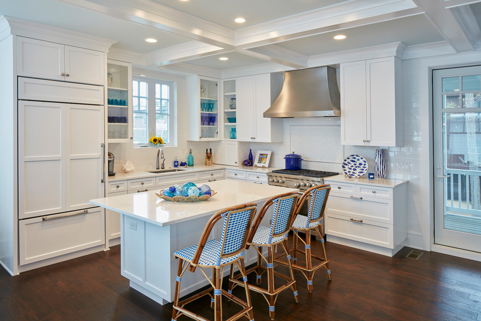 Inspiration for a large coastal l-shaped brown floor and dark wood floor open concept kitchen remodel in Other with an undermount sink, shaker cabinets, white cabinets, white backsplash, ceramic backsplash, paneled appliances and an island