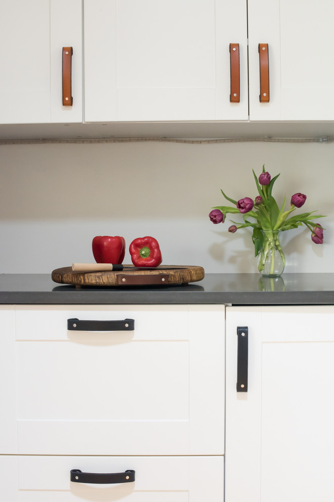 Foto di una cucina parallela design di medie dimensioni con lavello sottopiano, ante bianche, top in granito, paraspruzzi bianco, elettrodomestici bianchi, pavimento in bambù, pavimento beige e top grigio