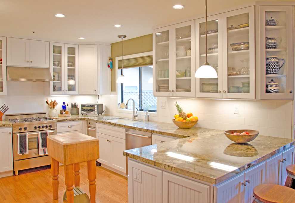 Inspiration for a modern u-shaped light wood floor enclosed kitchen remodel in San Francisco with glass-front cabinets, white cabinets, white backsplash, stainless steel appliances, an undermount sink and granite countertops