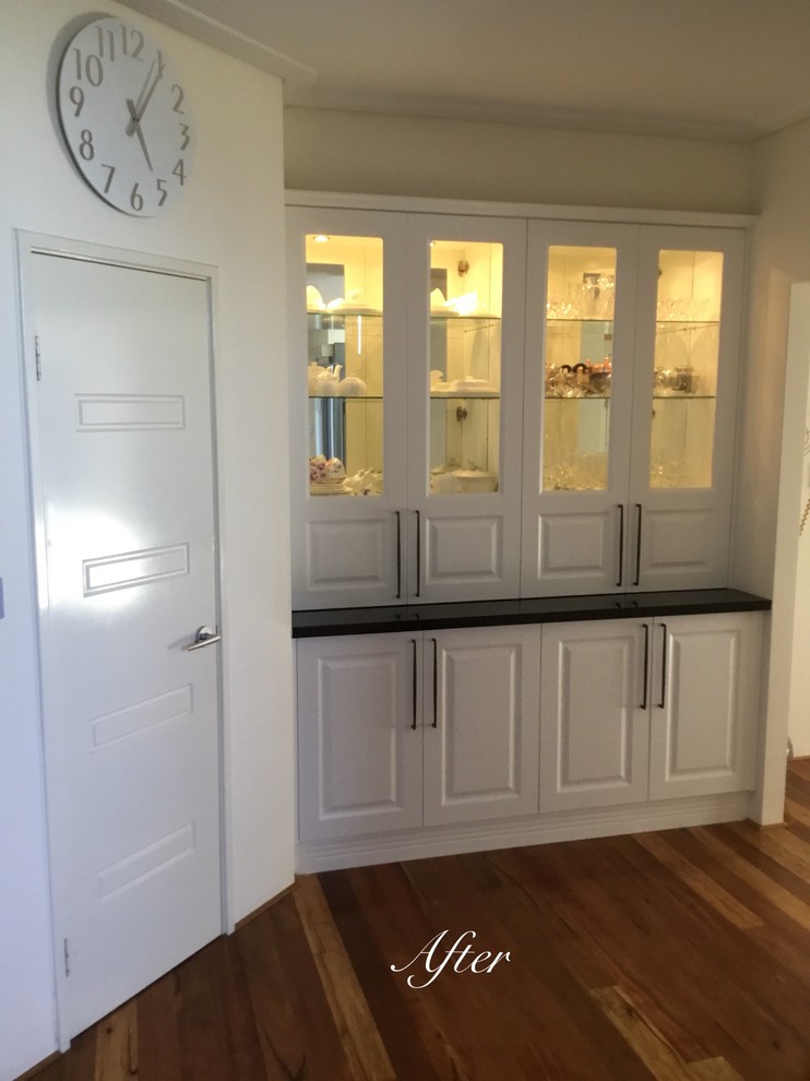 Imagen de cocina tradicional abierta con puertas de armario blancas y suelo de madera en tonos medios