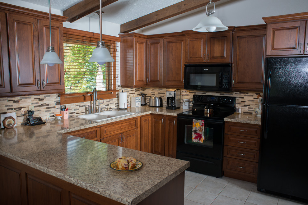 Amerikansk inredning av ett litet kök, med en dubbel diskho, luckor med upphöjd panel, skåp i mörkt trä, granitbänkskiva, stänkskydd i stickkakel, svarta vitvaror, klinkergolv i keramik, en halv köksö och grått golv