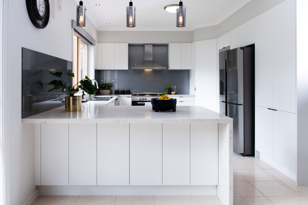 Inredning av ett modernt stort grå grått kök, med en undermonterad diskho, öppna hyllor, vita skåp, bänkskiva i kvarts, grått stänkskydd, glaspanel som stänkskydd, rostfria vitvaror, klinkergolv i porslin, en köksö och vitt golv