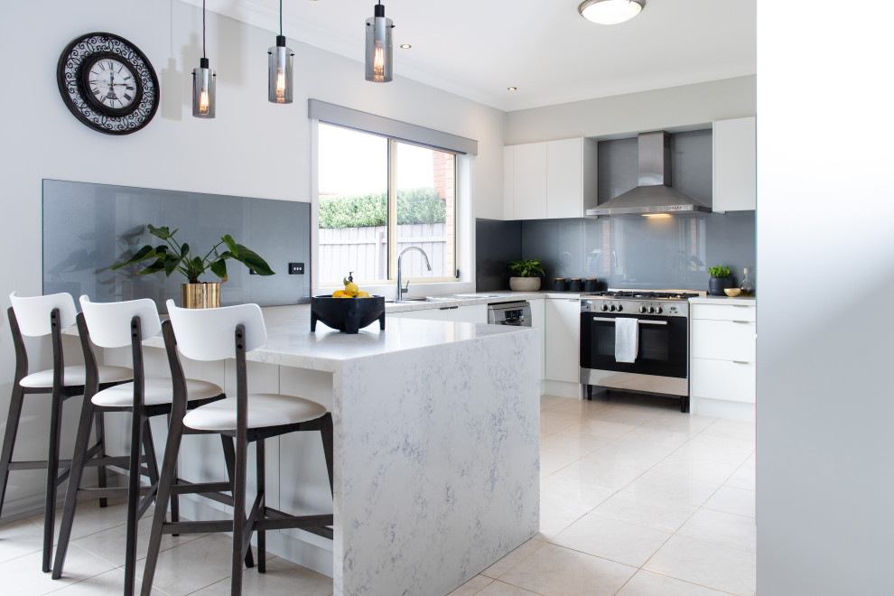Moderne Küche in U-Form mit flächenbündigen Schrankfronten, weißen Schränken, Küchenrückwand in Grau, Küchengeräten aus Edelstahl, Halbinsel, beigem Boden und weißer Arbeitsplatte in Melbourne
