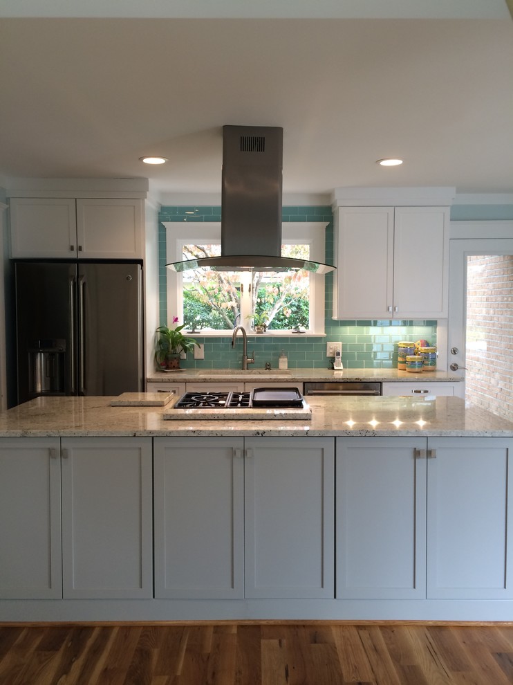 Photo of a small classic single-wall kitchen/diner in Other with a submerged sink, shaker cabinets, white cabinets, granite worktops, blue splashback, glass tiled splashback, stainless steel appliances, medium hardwood flooring and an island.
