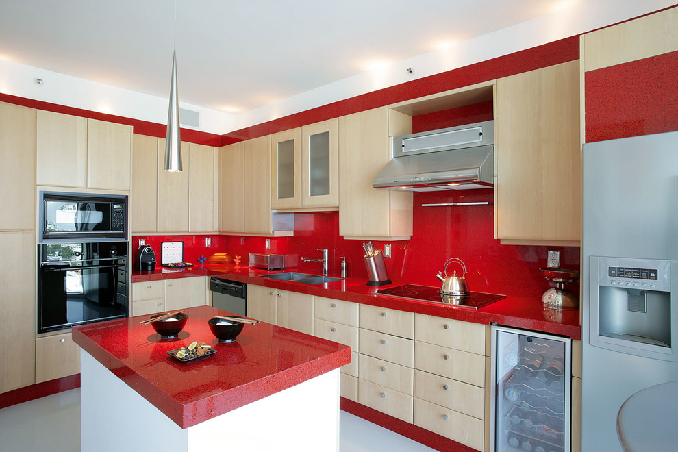 Foto på ett funkis röd l-kök, med en dubbel diskho, släta luckor, skåp i ljust trä och rött stänkskydd