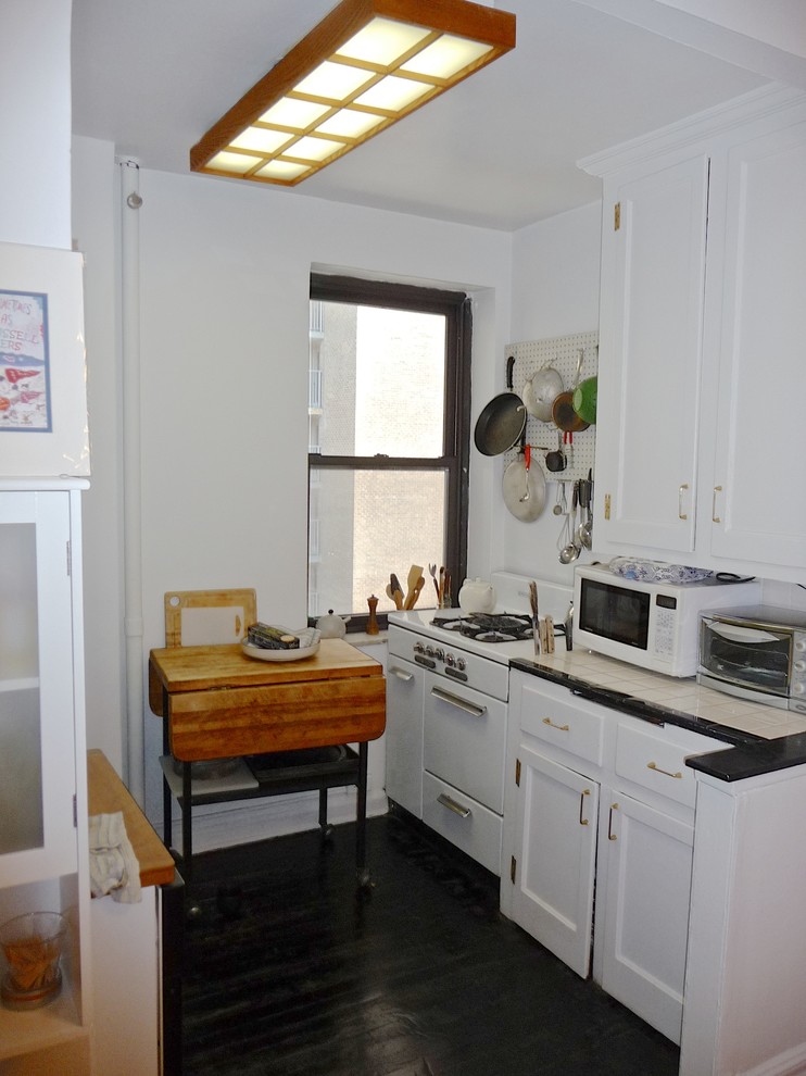 Cette image montre une cuisine ouverte parallèle minimaliste avec un évier encastré, un placard à porte plane, des portes de placard blanches, un plan de travail en quartz et un électroménager blanc.