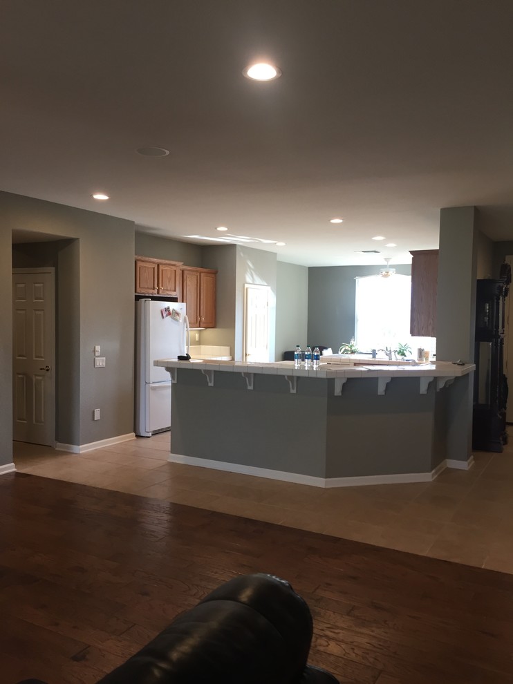 Large modern single-wall open plan kitchen in Sacramento with a submerged sink, flat-panel cabinets, black cabinets, engineered stone countertops, black appliances, medium hardwood flooring, an island, brown floors and black worktops.