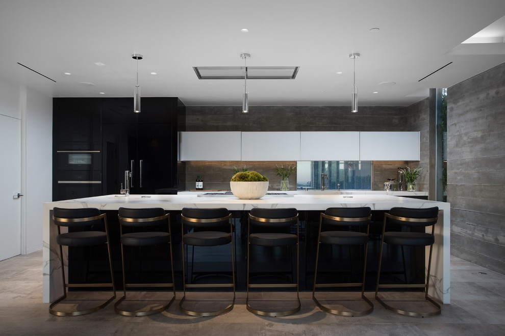 На фото: кухня в современном стиле с плоскими фасадами, серым фартуком, техникой под мебельный фасад, островом, серым полом, белой столешницей и черно-белыми фасадами с