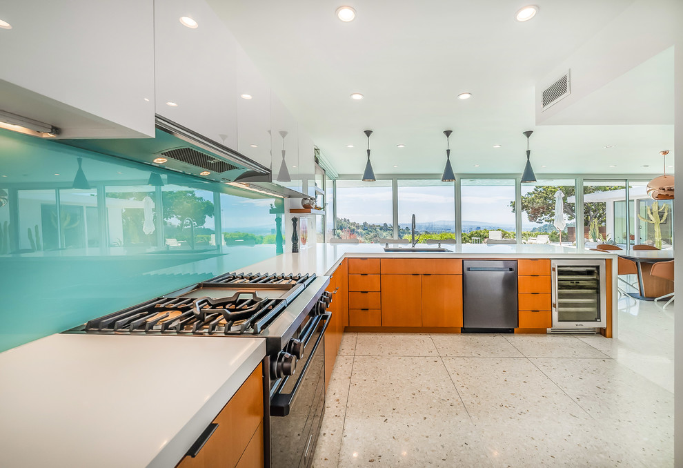 Medium sized contemporary l-shaped kitchen/diner in Los Angeles with a submerged sink, flat-panel cabinets, white cabinets, engineered stone countertops, blue splashback, glass sheet splashback, stainless steel appliances, terrazzo flooring, a breakfast bar, grey floors and white worktops.