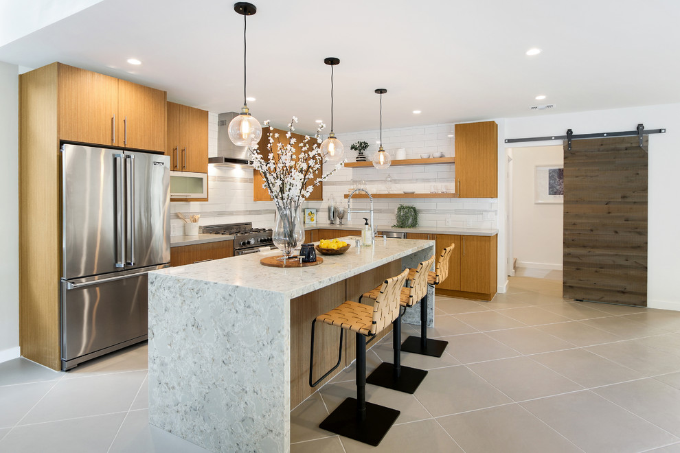 Eat-in kitchen - mid-sized 1960s l-shaped porcelain tile and gray floor eat-in kitchen idea in Los Angeles with a single-bowl sink, flat-panel cabinets, medium tone wood cabinets, quartz countertops, white backsplash, subway tile backsplash, stainless steel appliances and an island
