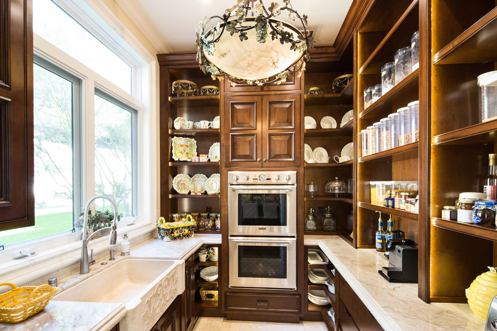 Exempel på ett mellanstort klassiskt u-kök, med luckor med upphöjd panel, rostfria vitvaror, en rustik diskho, skåp i mellenmörkt trä, kalkstensgolv och bänkskiva i kvartsit