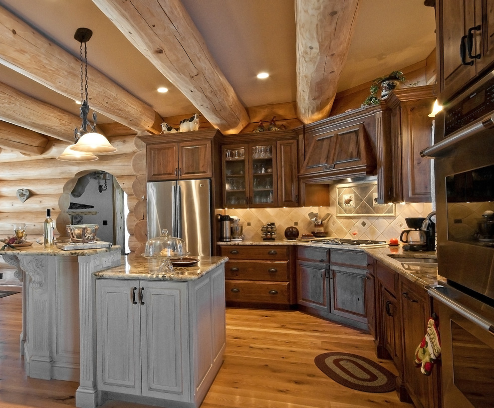 Immagine di una cucina rustica con lavello sottopiano, ante con bugna sagomata, ante in legno bruno, paraspruzzi beige e elettrodomestici in acciaio inossidabile