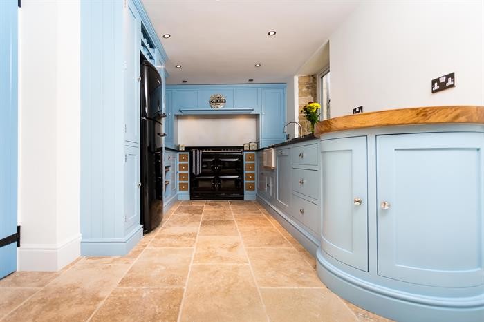 オックスフォードシャーにある高級な小さなトラディショナルスタイルのおしゃれなキッチン (シングルシンク、青いキャビネット、御影石カウンター、黒いキッチンパネル、黒い調理設備、ライムストーンの床、アイランドなし) の写真