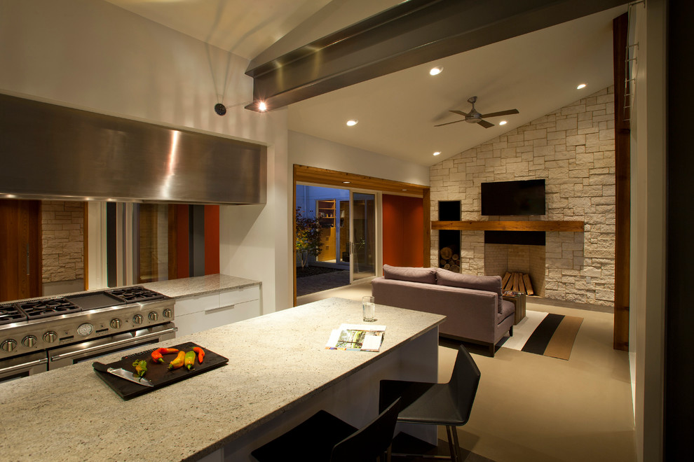 Exempel på ett modernt kök, med en undermonterad diskho, släta luckor, vita skåp, granitbänkskiva, vitt stänkskydd, glaspanel som stänkskydd och rostfria vitvaror