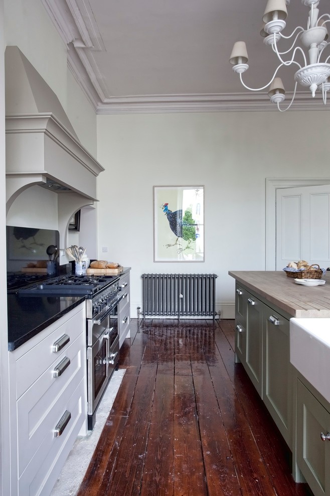 Inredning av ett klassiskt kök, med en rustik diskho, skåp i shakerstil, gröna skåp, rostfria vitvaror, mörkt trägolv och en köksö