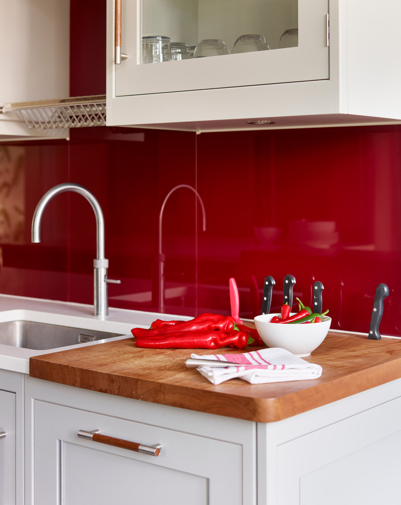 ロンドンにある高級な広いトランジショナルスタイルのおしゃれなキッチン (アンダーカウンターシンク、グレーのキャビネット、珪岩カウンター、赤いキッチンパネル、ガラス板のキッチンパネル) の写真