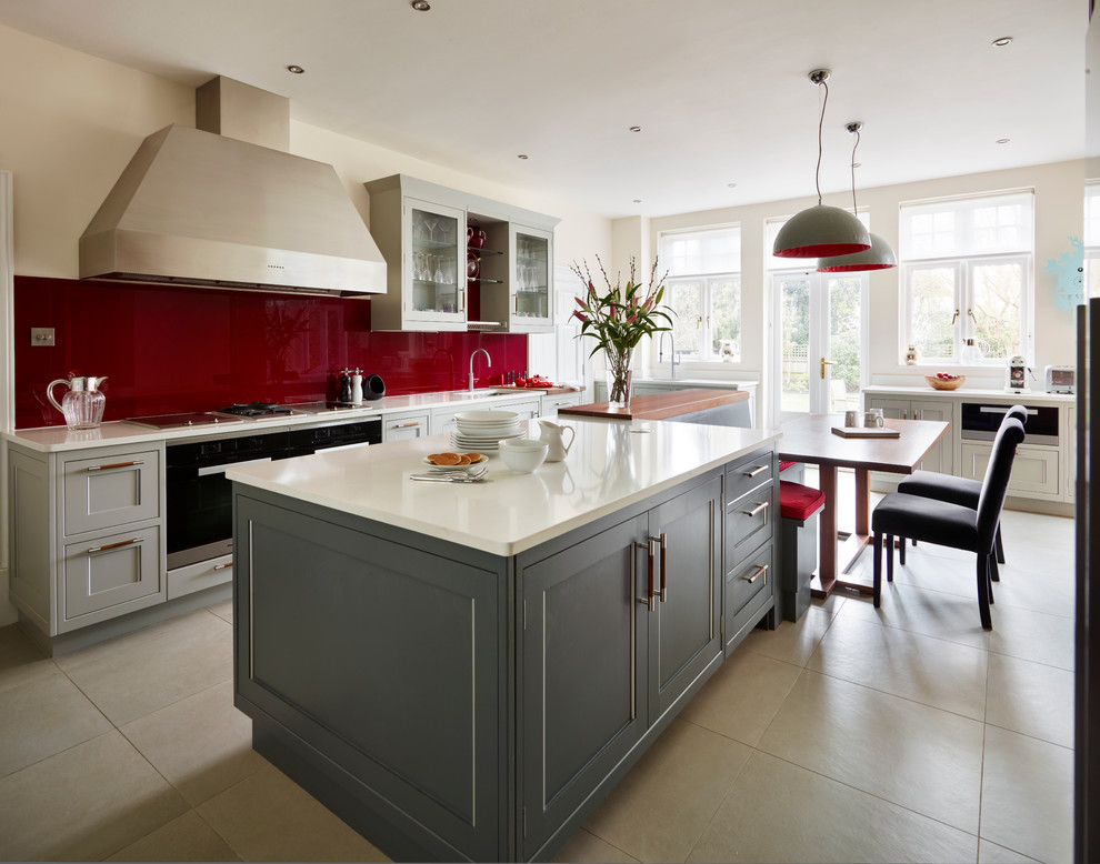 This is an example of a large traditional kitchen/diner in London with quartz worktops, red splashback, glass sheet splashback, integrated appliances, an island and grey cabinets.