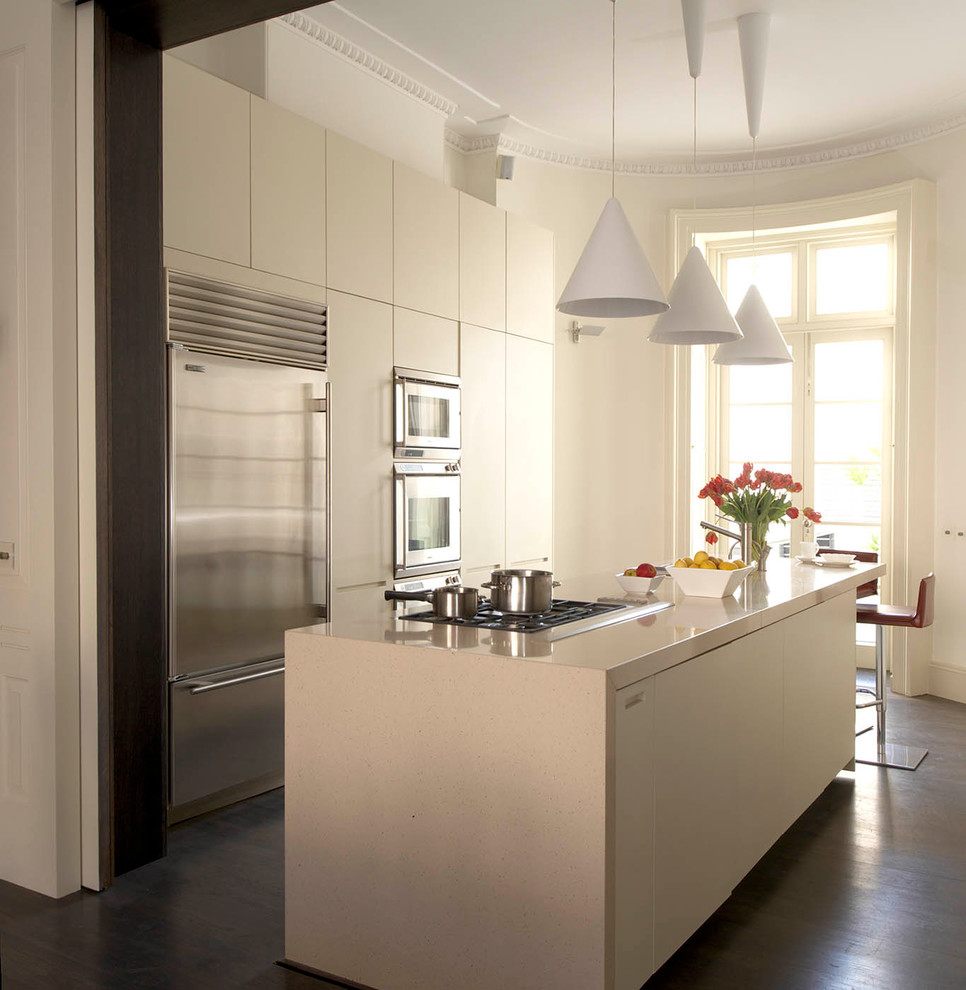 Zweizeilige Moderne Küche mit flächenbündigen Schrankfronten, weißen Schränken, Küchengeräten aus Edelstahl, dunklem Holzboden und Kücheninsel in London