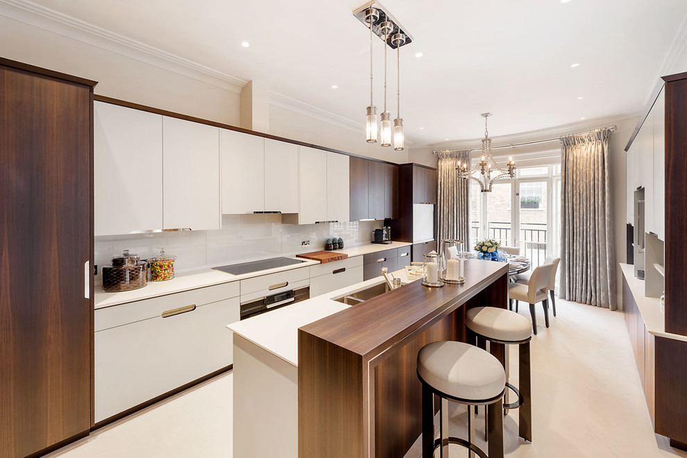 Design ideas for a medium sized contemporary galley open plan kitchen in London with a double-bowl sink, flat-panel cabinets, white cabinets, an island, white worktops, quartz worktops, glass sheet splashback, stainless steel appliances and white floors.