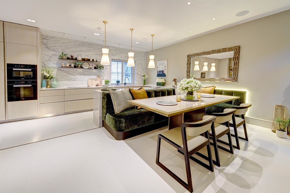 Large contemporary u-shaped kitchen/diner in London with flat-panel cabinets, light wood cabinets, marble worktops, marble splashback, porcelain flooring, white floors, black appliances and a breakfast bar.