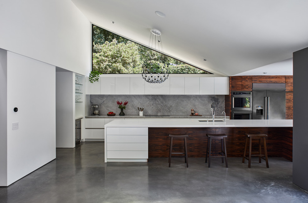 Idéer för ett stort retro grå kök, med en dubbel diskho, släta luckor, vita skåp, bänkskiva i kvartsit, grått stänkskydd, stänkskydd i sten, rostfria vitvaror, betonggolv, en köksö och grått golv