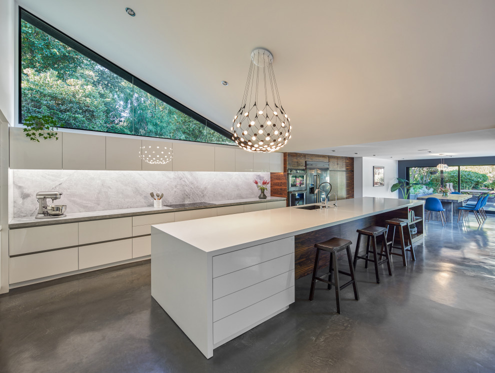 Inspiration for a huge 1960s l-shaped concrete floor and gray floor open concept kitchen remodel in Los Angeles with a double-bowl sink, flat-panel cabinets, white cabinets, quartzite countertops, gray backsplash, stone slab backsplash, stainless steel appliances, an island and gray countertops