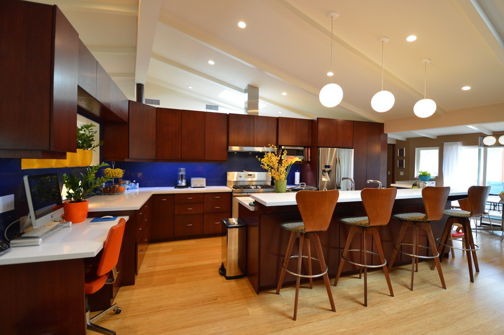 Example of a mid-century modern l-shaped light wood floor kitchen design in Los Angeles with a triple-bowl sink, flat-panel cabinets, blue backsplash, stone slab backsplash, stainless steel appliances and an island