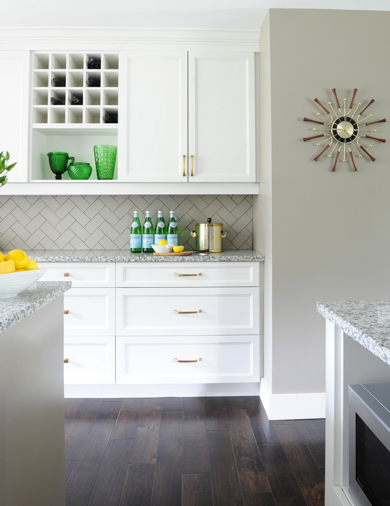 Imagen de cocina tradicional renovada con armarios con paneles empotrados, puertas de armario blancas, salpicadero beige, suelo de madera oscura y una isla