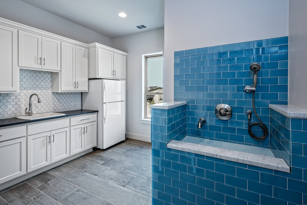Mid-sized transitional single-wall brown floor kitchen photo in Austin with a drop-in sink, shaker cabinets, white cabinets, solid surface countertops, white backsplash, ceramic backsplash and white appliances