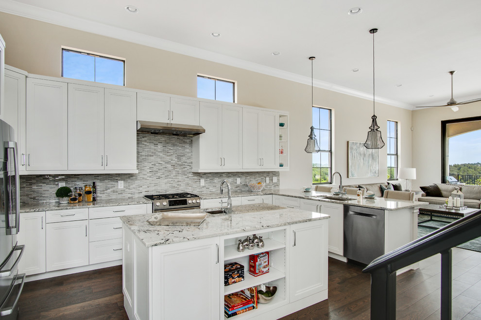 Modern inredning av ett stort flerfärgad flerfärgat kök, med en undermonterad diskho, luckor med infälld panel, vita skåp, granitbänkskiva, flerfärgad stänkskydd, stänkskydd i glaskakel, rostfria vitvaror, mörkt trägolv, en köksö och brunt golv