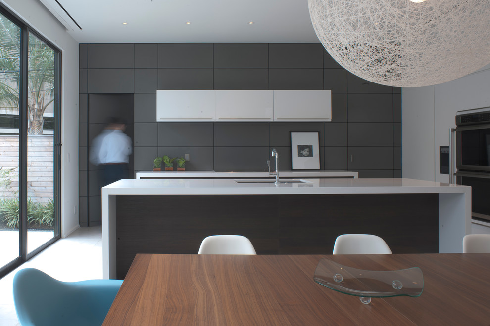 Modern inredning av ett kök, med bänkskiva i kvarts, en undermonterad diskho, släta luckor, vita skåp och rostfria vitvaror