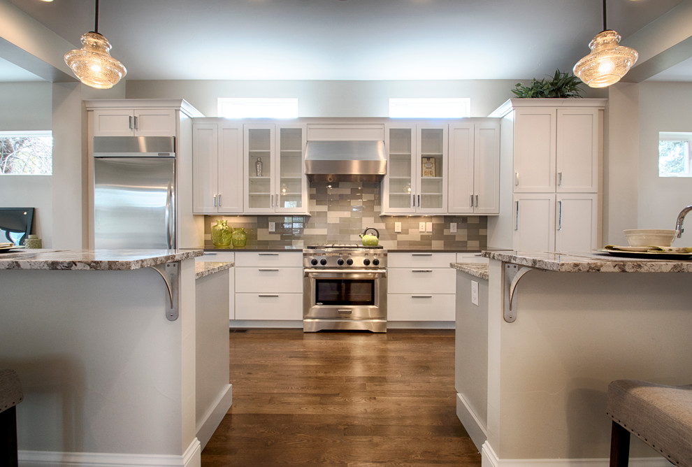 This is an example of a large modern l-shaped kitchen/diner in Denver with shaker cabinets, white cabinets, stainless steel appliances, medium hardwood flooring and multiple islands.
