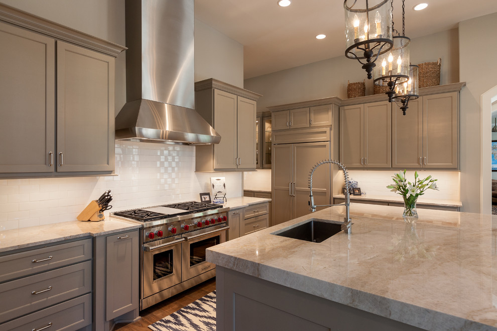 Elegant dark wood floor kitchen photo in Houston with an undermount sink, recessed-panel cabinets, beige cabinets, white backsplash, subway tile backsplash, stainless steel appliances, an island and beige countertops