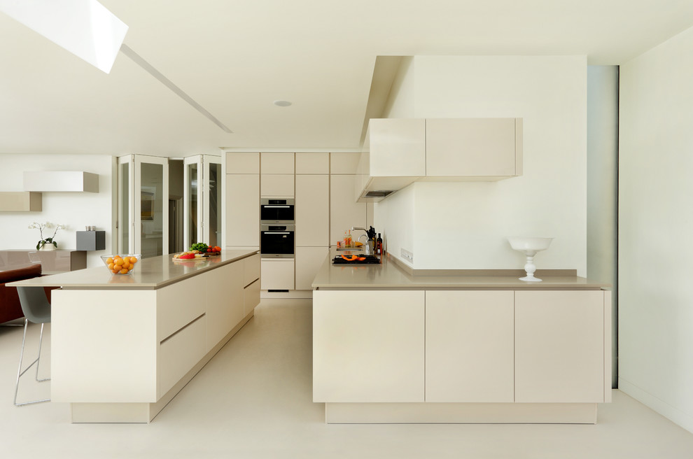 Large contemporary kitchen in London with flat-panel cabinets, beige cabinets, stainless steel appliances and an island.