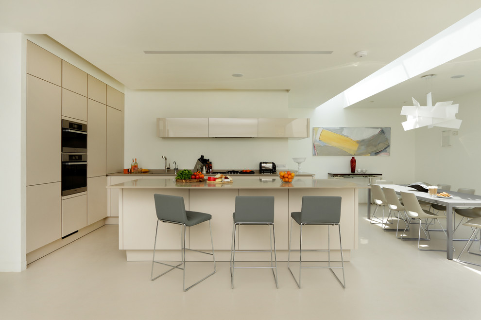 Große Moderne Wohnküche mit flächenbündigen Schrankfronten, beigen Schränken, Küchengeräten aus Edelstahl, Kücheninsel und integriertem Waschbecken in London