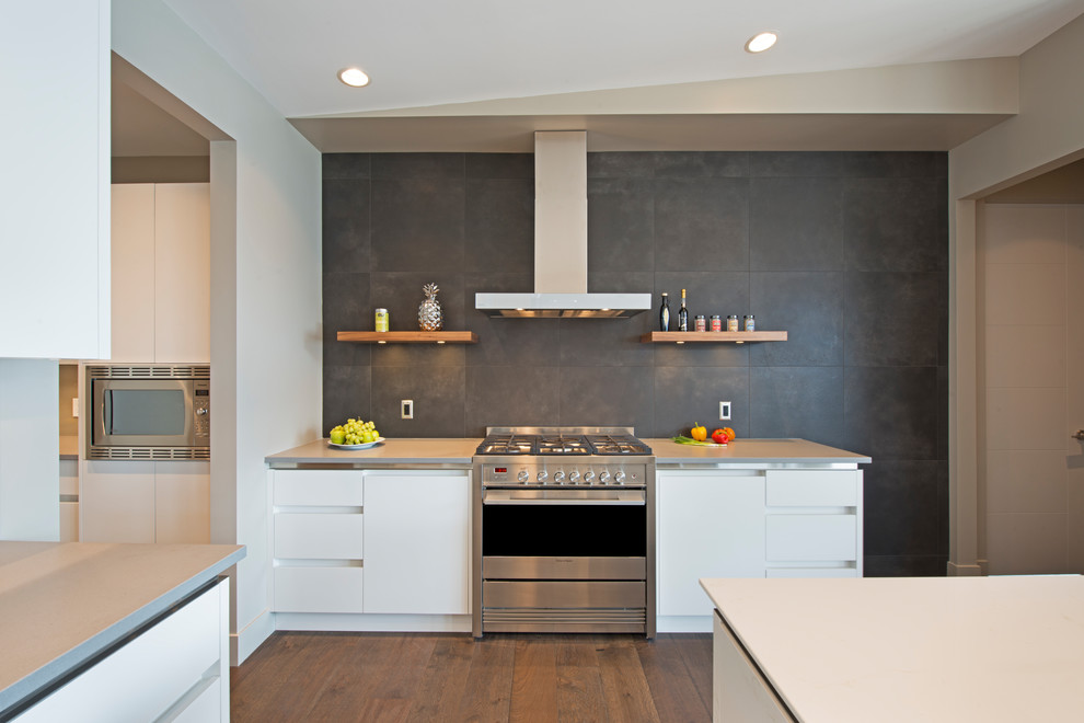 This is an example of a large contemporary kitchen/diner in Other with a submerged sink, flat-panel cabinets, engineered stone countertops, black splashback, porcelain splashback, stainless steel appliances, an island and white worktops.