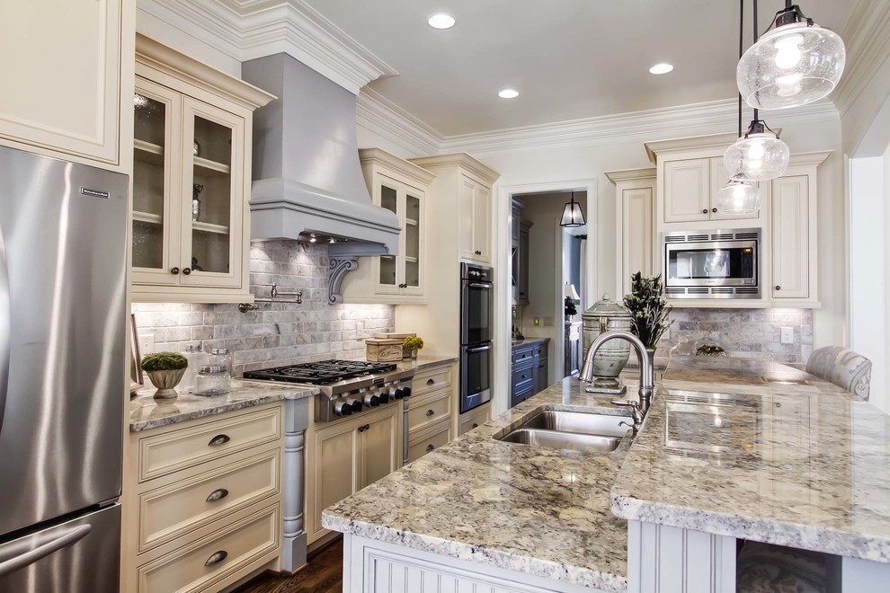 Inspiration for a mediterranean u-shaped eat-in kitchen remodel in Nashville with an undermount sink, beaded inset cabinets, white cabinets, granite countertops, beige backsplash, stone tile backsplash and stainless steel appliances