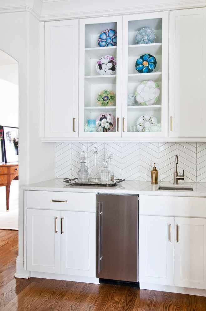 Bild på ett avskilt, mellanstort vintage vit vitt u-kök, med en undermonterad diskho, skåp i shakerstil, vita skåp, bänkskiva i kvarts, vitt stänkskydd, stänkskydd i keramik, rostfria vitvaror, mellanmörkt trägolv, en köksö och brunt golv