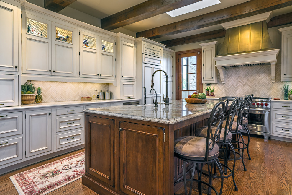 Inspiration for a large timeless l-shaped medium tone wood floor and brown floor eat-in kitchen remodel in Nashville with a farmhouse sink, recessed-panel cabinets, white cabinets, quartz countertops, beige backsplash, stone tile backsplash, paneled appliances, an island and multicolored countertops