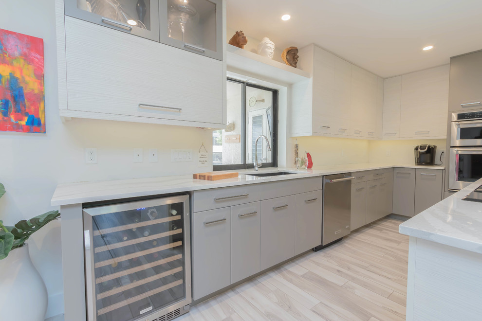 Large modern l-shaped open plan kitchen in Other with a submerged sink, flat-panel cabinets, grey cabinets, engineered stone countertops, ceramic splashback, stainless steel appliances, porcelain flooring, an island and grey floors.