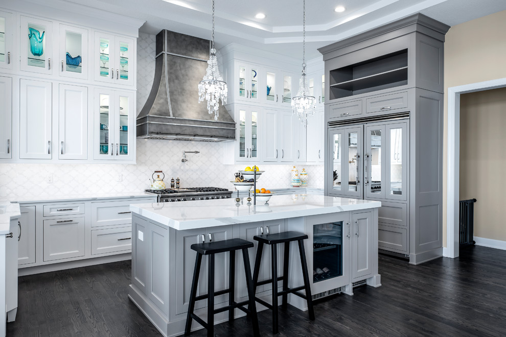 Expansive traditional u-shaped enclosed kitchen in Tampa with a submerged sink, white cabinets, engineered stone countertops, white splashback, mosaic tiled splashback, integrated appliances, dark hardwood flooring, an island, white worktops, shaker cabinets and grey floors.