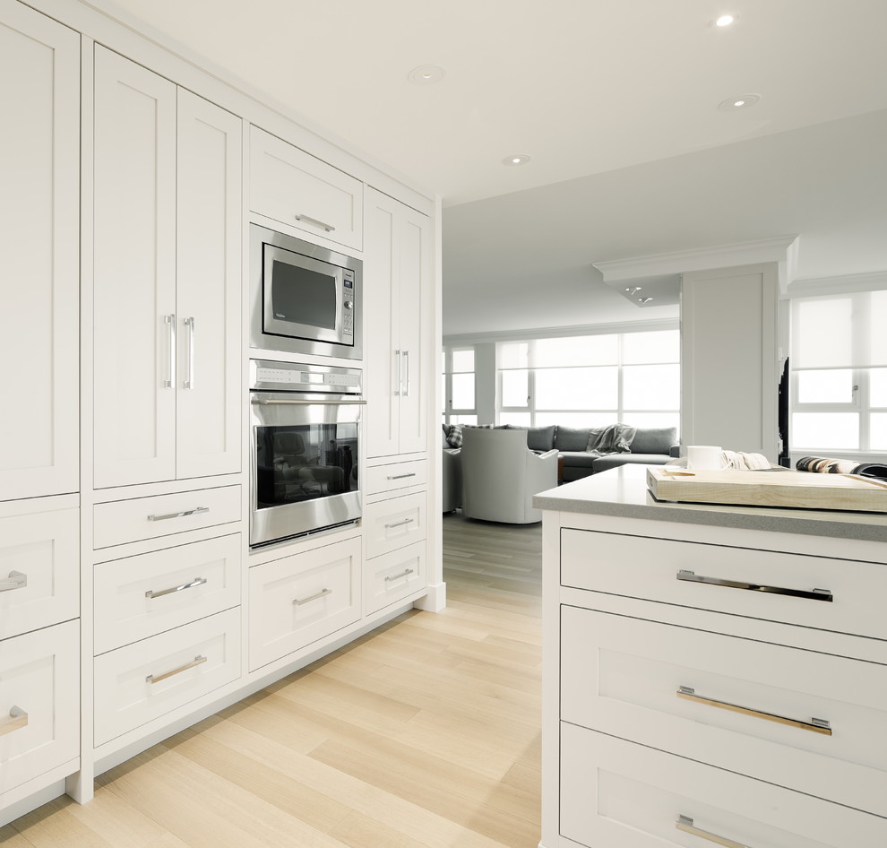 Photo of a medium sized traditional u-shaped kitchen/diner in Vancouver with shaker cabinets, grey cabinets, engineered stone countertops, ceramic splashback, stainless steel appliances, light hardwood flooring and an island.