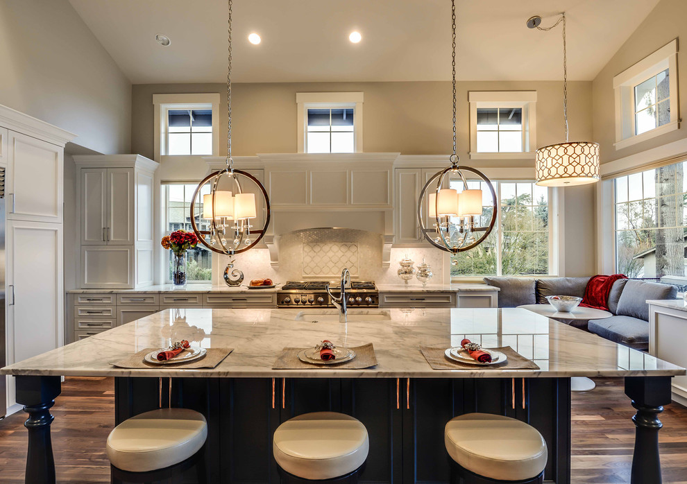 Expansive traditional l-shaped kitchen/diner in Seattle with a double-bowl sink, marble worktops, stainless steel appliances, dark hardwood flooring, an island, recessed-panel cabinets, white cabinets, brown floors and beige worktops.