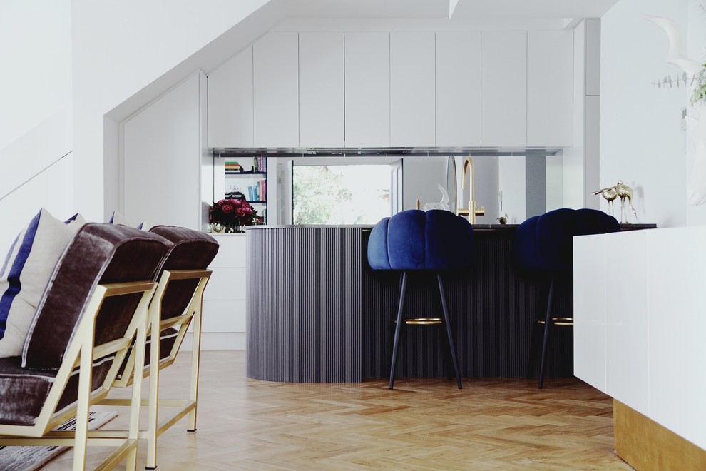 Exemple d'une cuisine ouverte parallèle tendance avec un placard à porte plane, des portes de placard blanches, une crédence miroir, un sol en bois brun, une péninsule, un sol marron et un plan de travail gris.