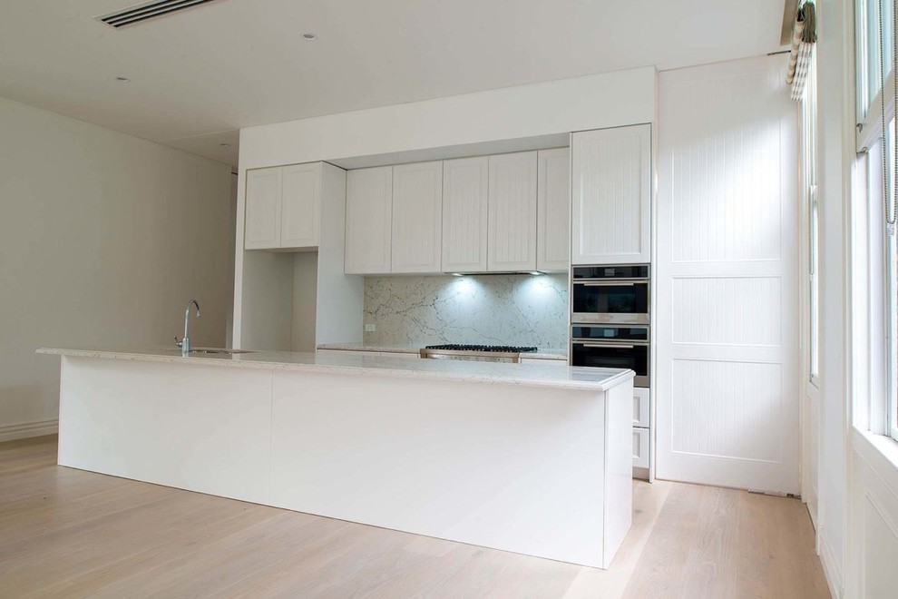 Esempio di una cucina moderna di medie dimensioni con lavello a doppia vasca, ante lisce, ante bianche, top in quarzo composito, paraspruzzi bianco, parquet chiaro e top bianco